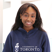 Azza Osman, seen from the chest up, wearing a University of Toronto pull over, and medium length brown hair, smiling
