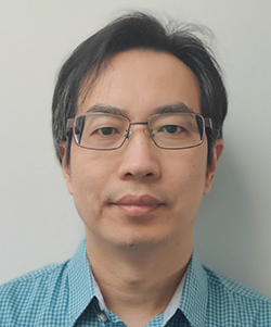 Wei Wu, seen from the shoulders up, wearing a blue collared shirt, glasses, and short black hair