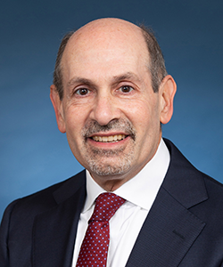 Jerry H. Gurwitz, seen from the chest up, wearing a suit and red tie and smiling