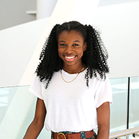 Massoma Kisob, seen from the waist up, wearing a white t-shirt and curly black hair
