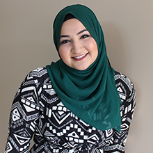 Shereen Khattab, seen from the chest up, wearing a black and white patterned shirt, green hijab, and smiling