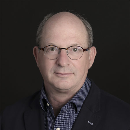 Steven Narod, seen from the chest up, wearing a blue collared shirt, black blazer, and glasses
