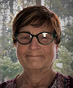 ELIZABETH KONIGSHAUS, seen from the shoulders up, wearing glasses and short brown hair